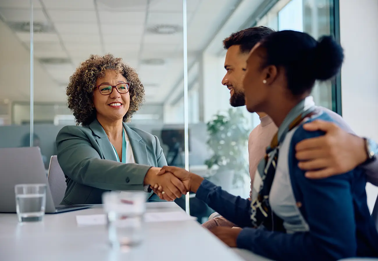 A black female financial advisor meeting with a young Black couple to develop an investment management strategy.