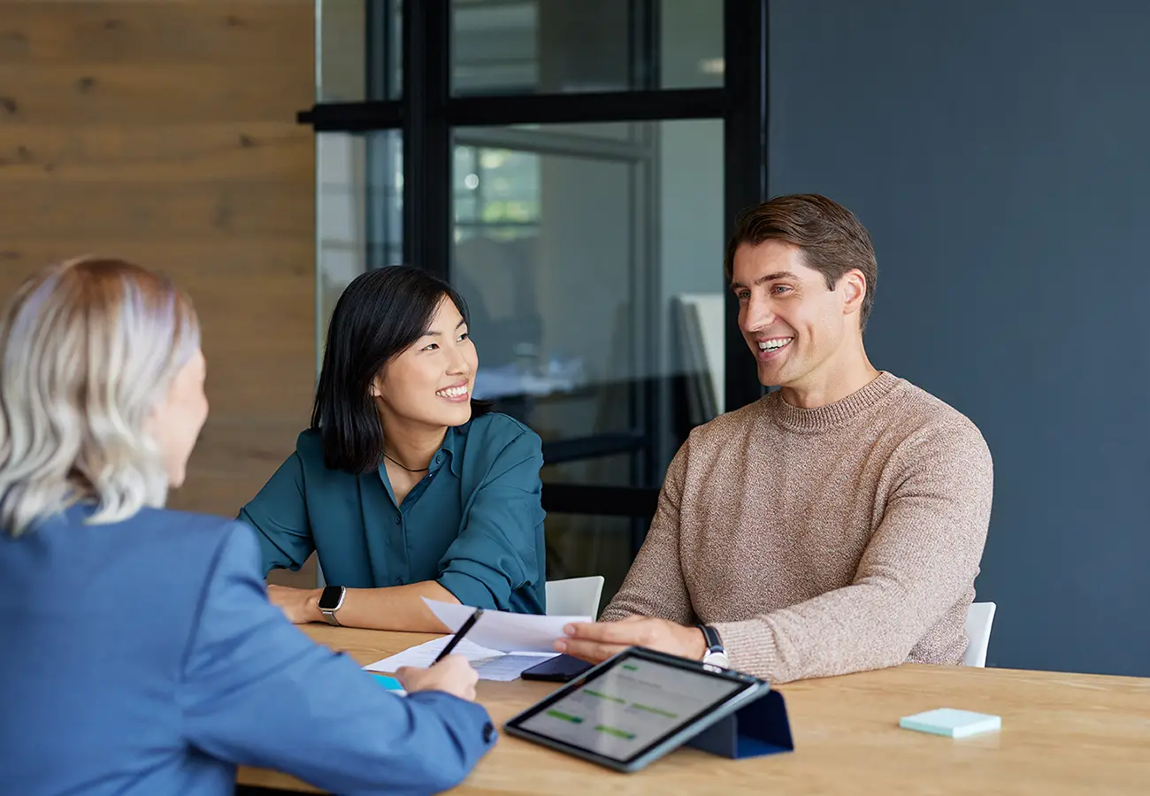 Skilled financial advisor meeting with a young mixed race couple to discuss tax and wealth strategy.